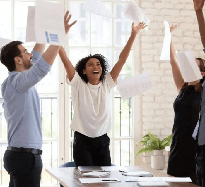 A group of co-workers celebrating and throwing paper into the air