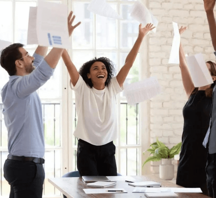 A group of co-workers celebrating and throwing paper into the air