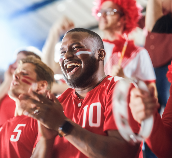 A man with face paint on at a soccer game cheering