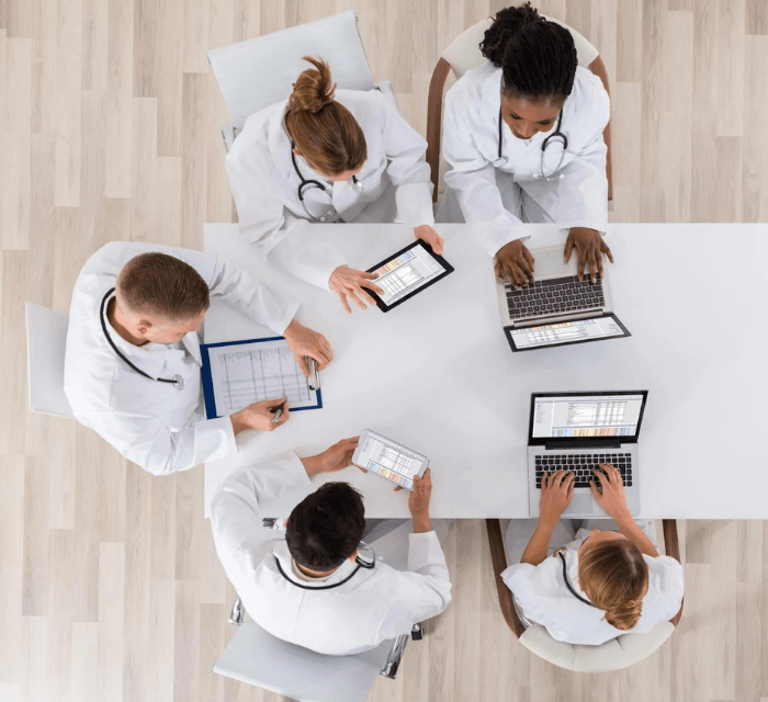 A group of doctors working at a desk on their laptops