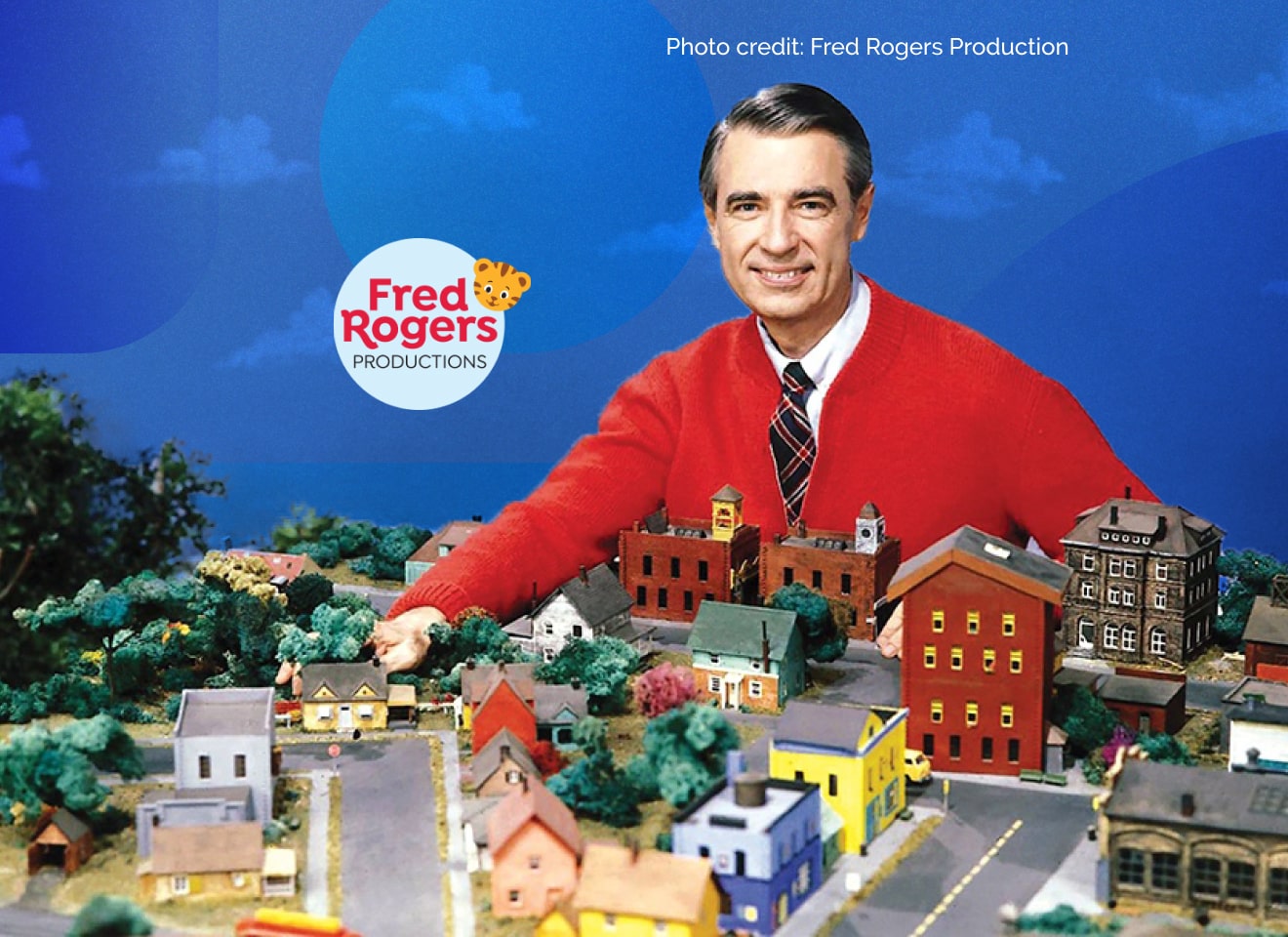 Fred Rogers at a table with a model town on it,