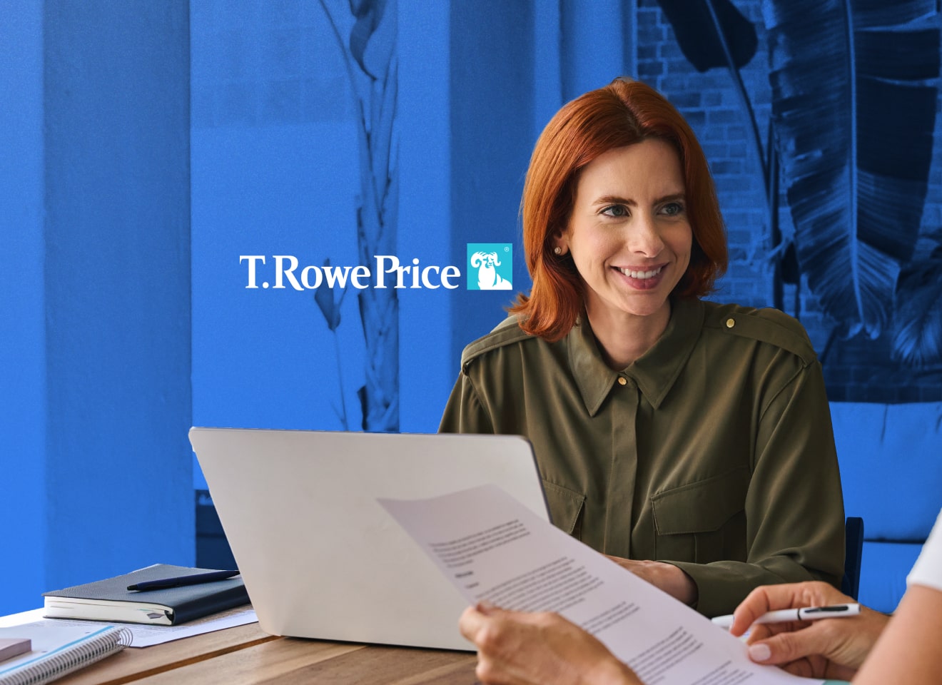 Woman working at a laptop on a desk with the T. Rowe Price logo over her shoulder.