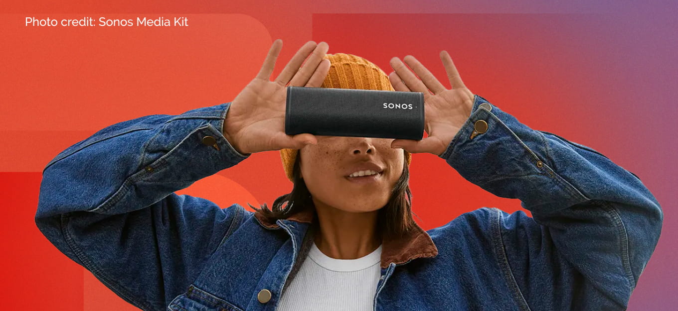 Asian woman in an orange beanie and denim jacket holding the SONOS Roam 2 in Block over her eyes posing