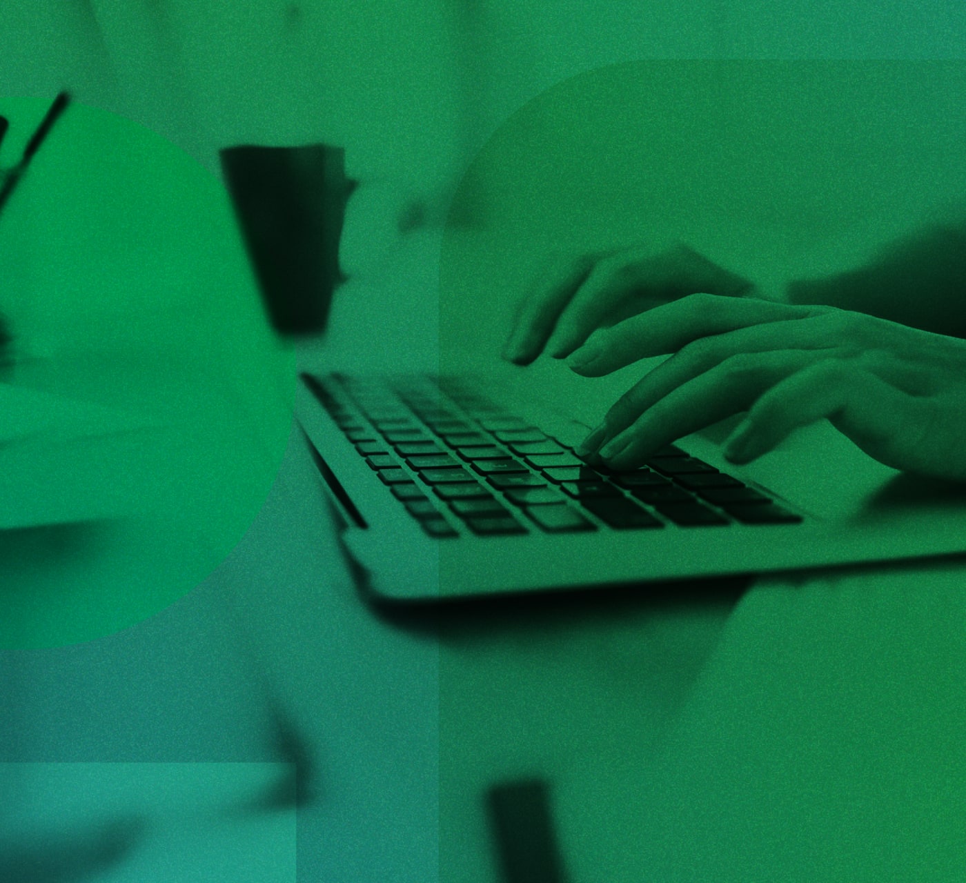 hands typing on a laptop placed on a desk. The laptop is surrounded by papers on the desk and a coffee cup in the back. There is a green overlay on the image.