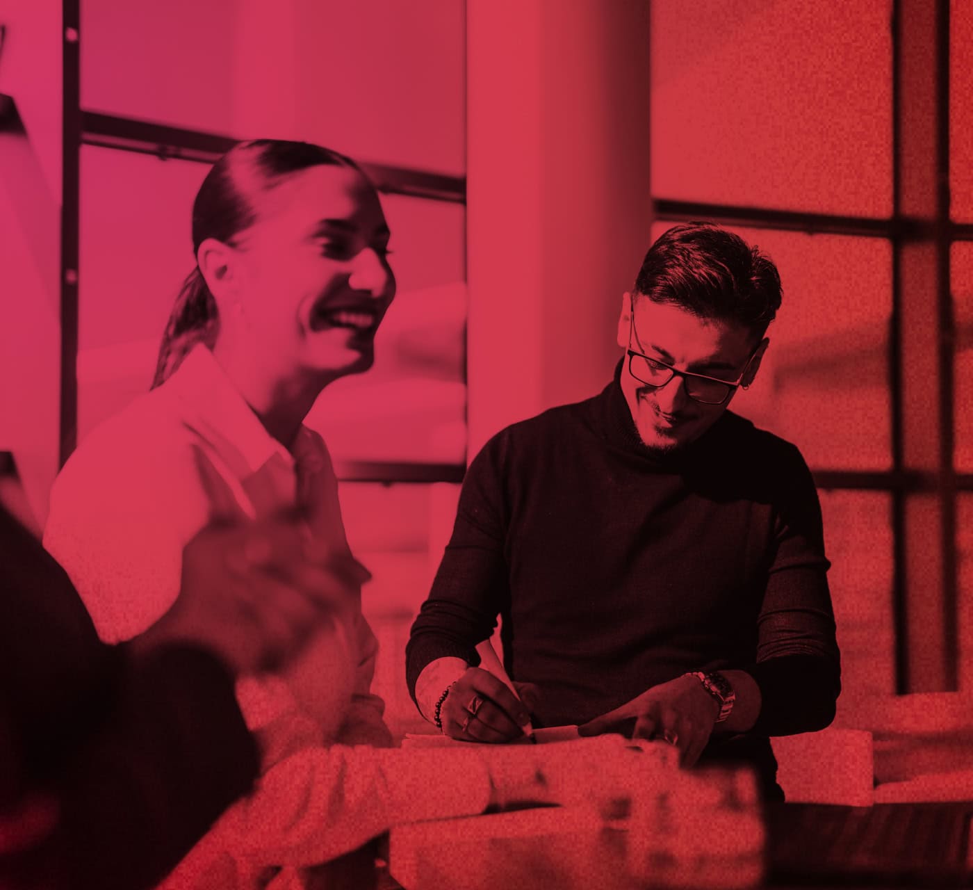 magenta red gradient image of three colleagues working around a table together smiling