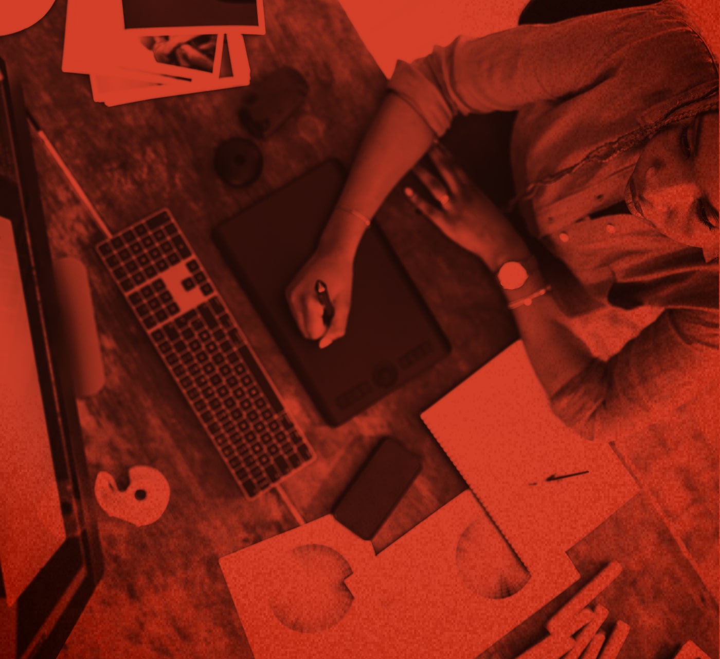 person typing on a laptop set atop a desk with papers all around and a red overlay.