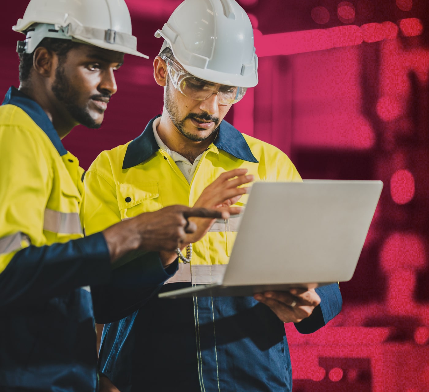 Two men in hardhats and high visibility coats looking at a laptop viewing their DAM for manufacturing platform