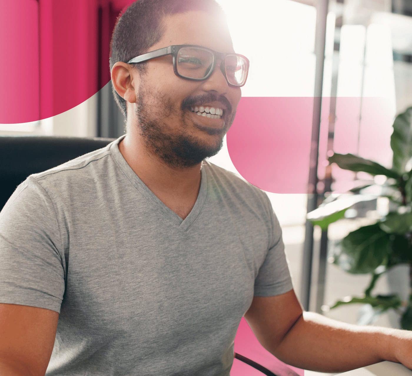 man in glasses smiling as he works on his laptop