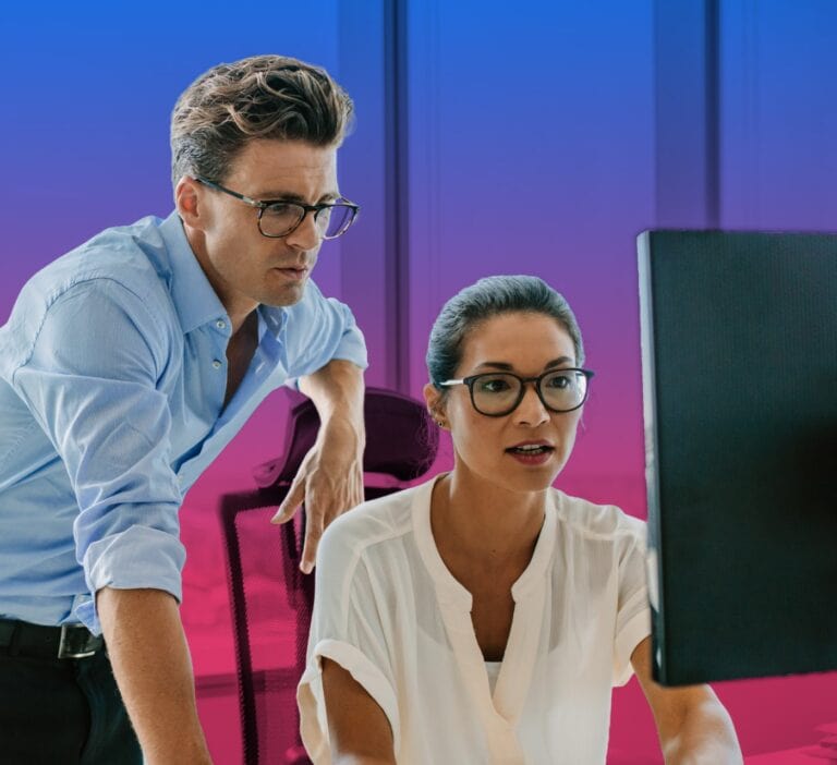 Two people looking at a computer screen and researching the best project management software available