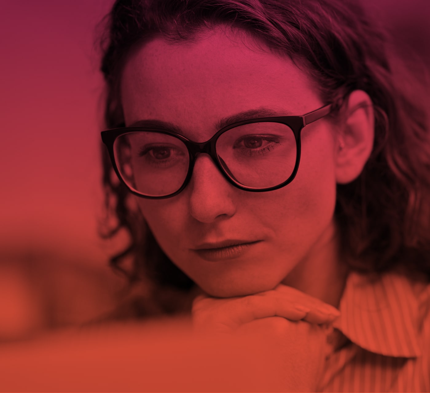 woman with long brown hair and glasses reading something with her hands below her chin. Set on a red background