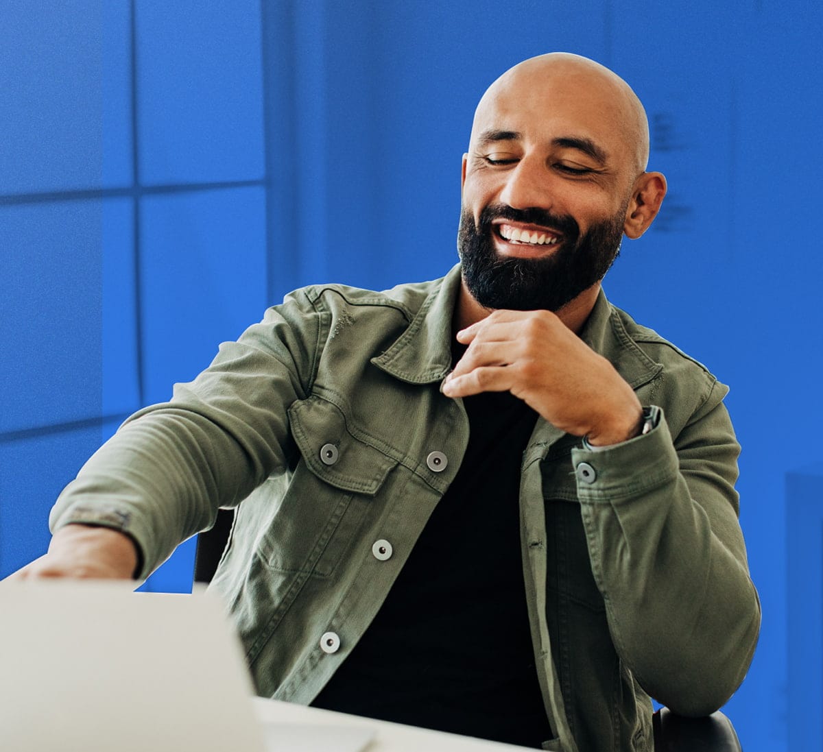 Laughing man with a cool beard working on a macbook pro