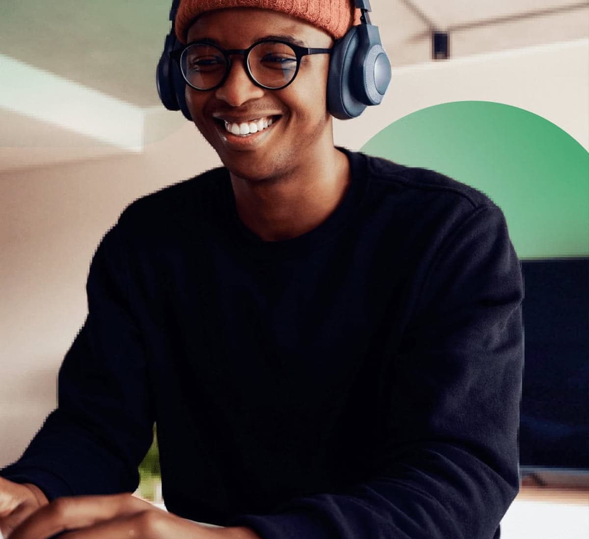 Designer wearing a hat and headphones working on a laptop