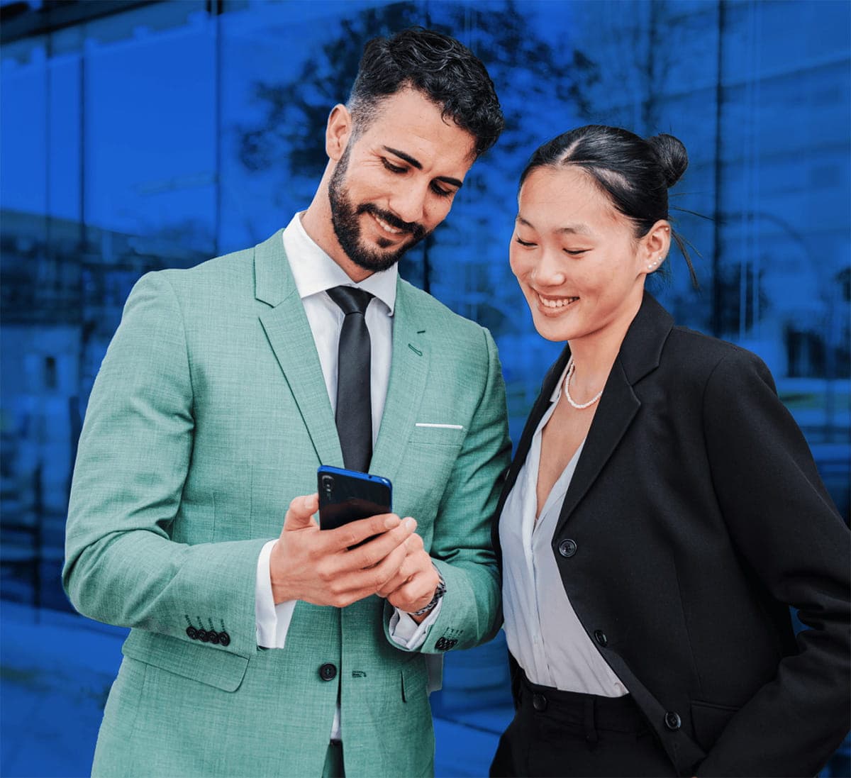 Smiling man and woman in business suits looking at a mobile phone