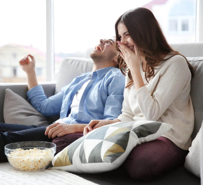 two people watching TV eating popcorn and laughing